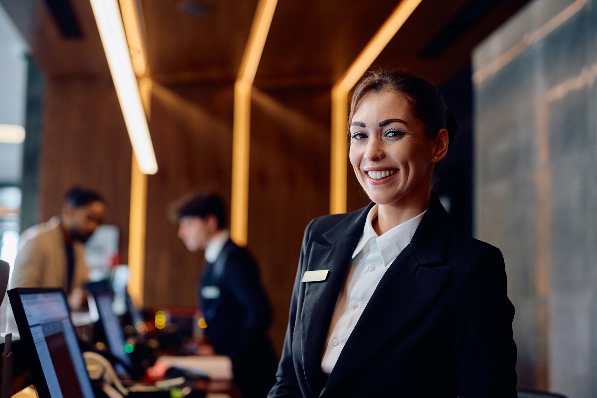 happy-female-concierge-at-front-desk-in-a-hotel-lo-2024-12-13-22-04-59-utc-1