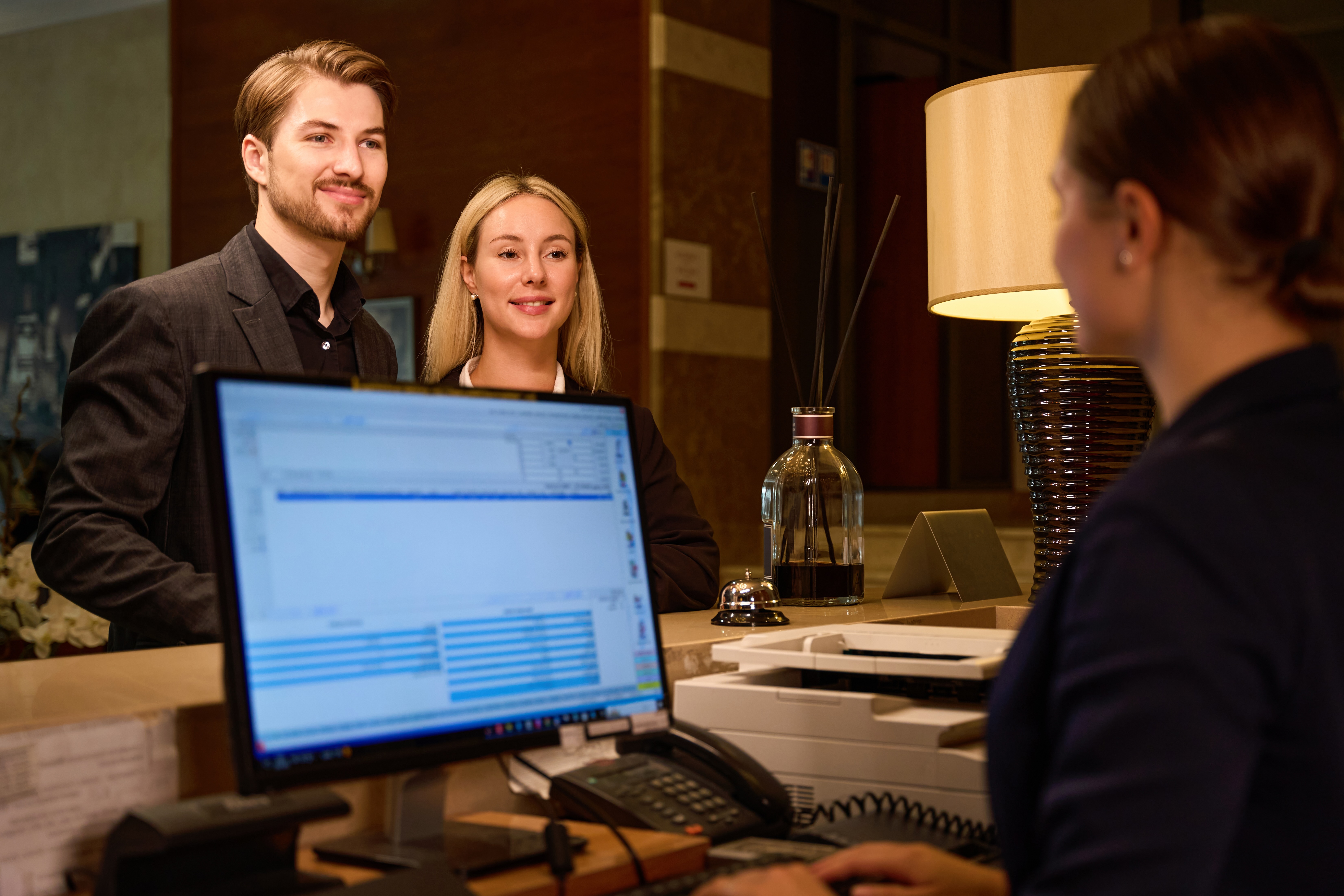host-typing-on-computer-while-couple-stand