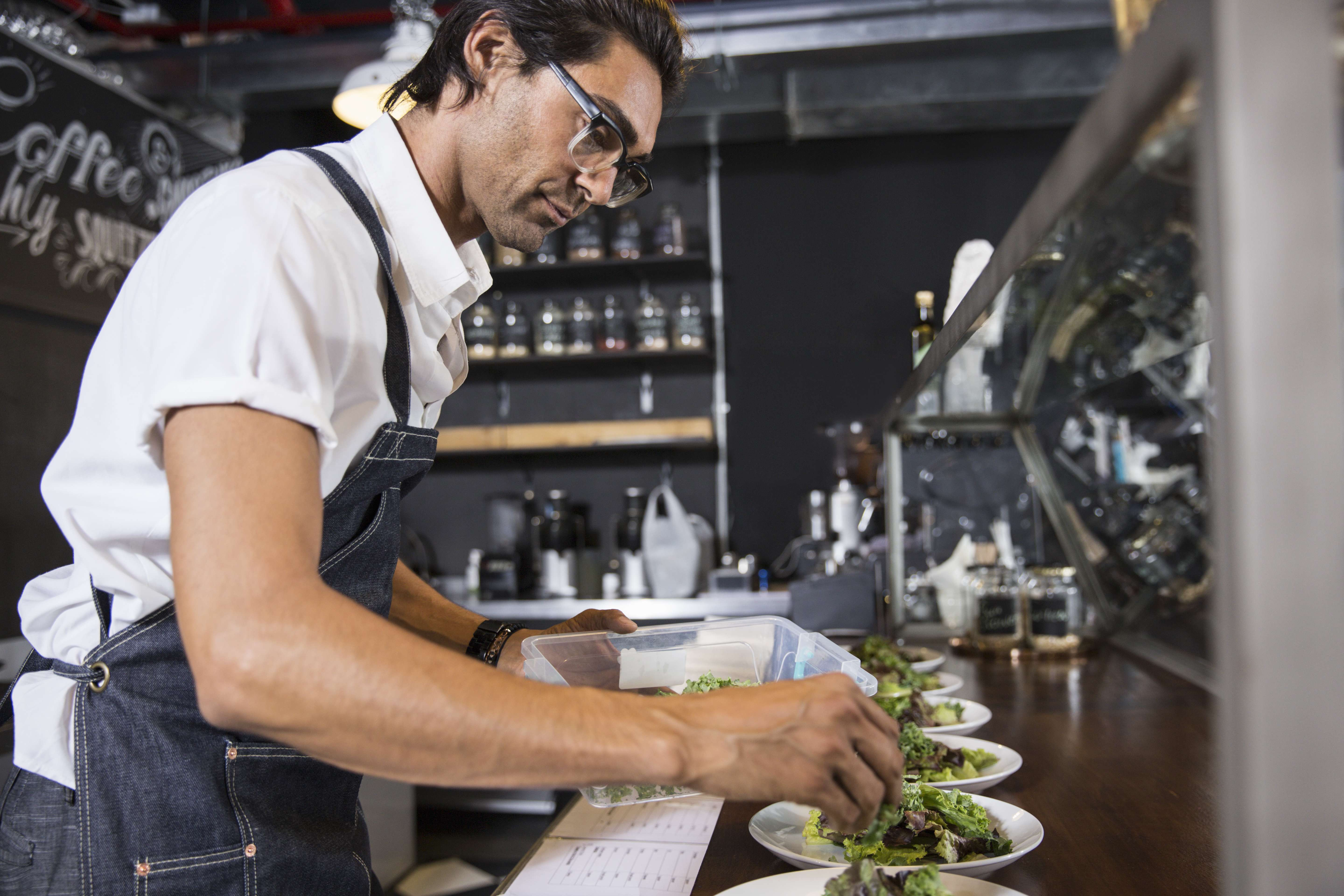 restaurateur-preparing-salad-behind-service-counte-2024-10-21-10-14-00-utc